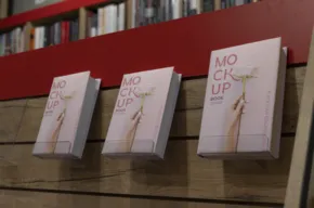 Three identical books with pink covers titled "no chick up" displayed on a wooden shelf against a red backdrop, serving as a mockup. - PSD Mockup