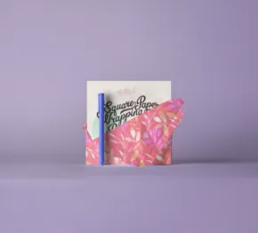 A book with a colorful cover stands against a purple background, partially obscured by pink crumpled paper. - PSD Mockup