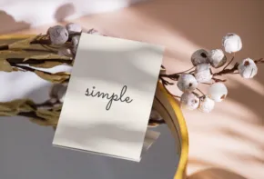 A note labeled "simple" attached to a wreath with white berries, set against a soft-focus background serves as a perfect mockup. - PSD Mockup