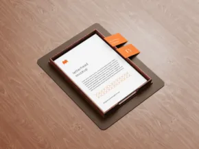 A digital tablet displaying a template, with an orange stylus on top, resting on a wooden surface. - PSD Mockup