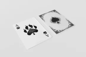 Two playing cards on a white surface; one with a black paw print and the other with a detailed ink blot design, serving as templates. - PSD Mockup