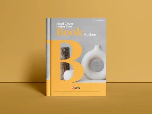 A book with a yellow spine and cover design featuring a letter "b" stands upright against a yellow backdrop, serving as an ideal mockup. - PSD Mockup