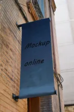 A black banner mockup hanging on the side of a building. - PSD Mockup