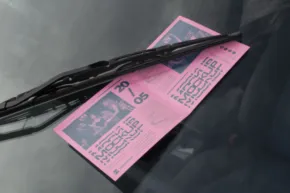A pink ticket mockup is on the windshield of a car. - PSD Mockup