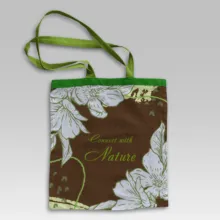 A brown and green mockup tote bag template with flowers on it. - PSD Mockup
