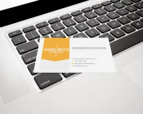 A business card template sitting on top of a laptop keyboard. - PSD Mockup