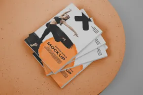 A magazine mockup on a circular table with an orange background. - PSD Mockup
