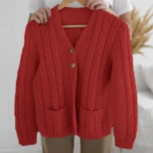 A woman is holding up a red knitted cardigan mockup. - PSD Mockup