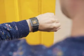 A person wearing a smart watch in front of a yellow door mockup. - PSD Mockup