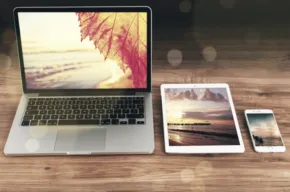 A laptop, phone and tablet on a wooden table, creating a template. - PSD Mockup