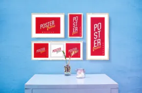 Four framed posters on a table in front of a blue wall, serving as a perfect template for showcasing artwork or as a mockup. - PSD Mockup