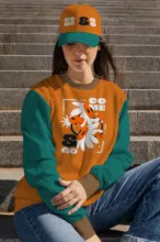 A woman wearing an orange and teal sweatshirt sitting on steps. - PSD Mockup