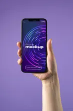 A hand holding up a phone with a purple background. - PSD Mockup