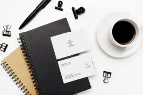 A black notebook with business cards and a cup of coffee is the perfect template for your project. - PSD Mockup
