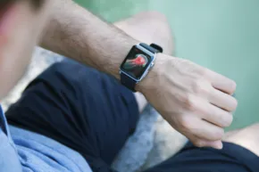 A man is sitting on a rock with an apple watch mockup on his wrist. - PSD Mockup