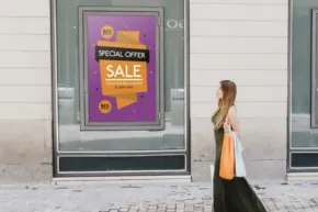 A woman walking past a store with a sale sign, creating a template for promotional materials. - PSD Mockup
