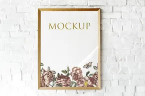 A gold frame with flowers hanging on a brick wall mockup. - PSD Mockup