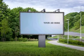 A large billboard in the middle of a grassy field serves as a perfect mockup for advertising. - PSD Mockup