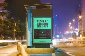 A green billboard mockup on the side of a street at night. - PSD Mockup